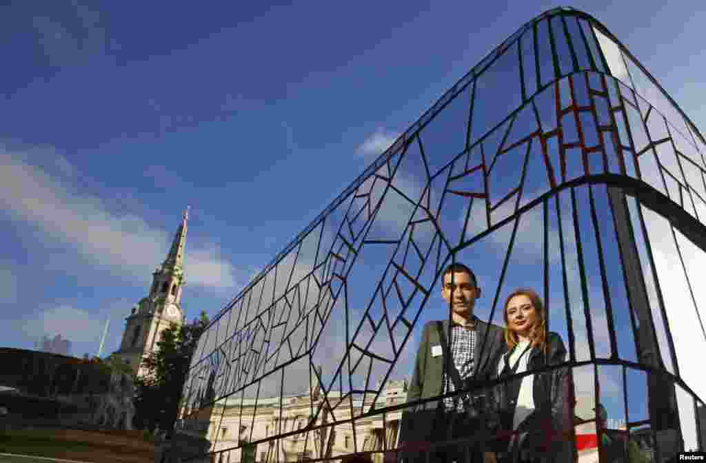 Artists Pawel (L) and Ewelina Srokowski are reflected in their new Routemaster bus mosaic sculpture entitled &quot;Invisible to the Environment&quot; at Trafalgar Square in London. The sculpture is part of a collection of 60 bus sculptures decorated by artists that will be placed across the capital, before being auctioned for charity in 2015. 