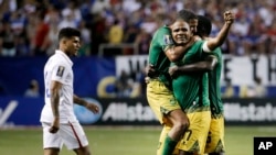 Jamaica’s Rudolph Austin, facing camera, celebrates with teammates Joel McAnuff, left, and Je-Vaughn Watson, right, as United States’ DeAndre Yedlin walks off the pitch after Jamaica defeated the United States 2-1 in a CONCACAF Gold Cup soccer semifinal W