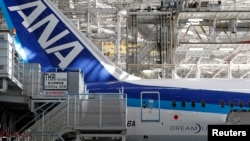 2013年4月28日，在全日空航空公司（ANA）的波音787梦幻客机下面，人们从事维修工作。