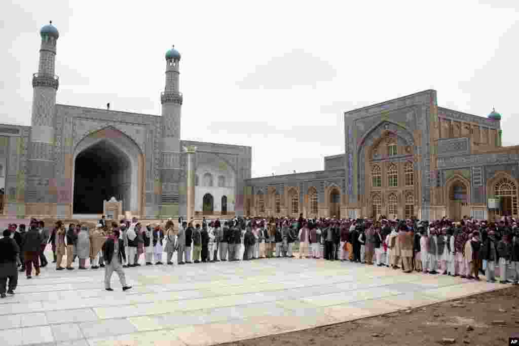 Afghan men line up before casting their votes in a polling station in Herat.