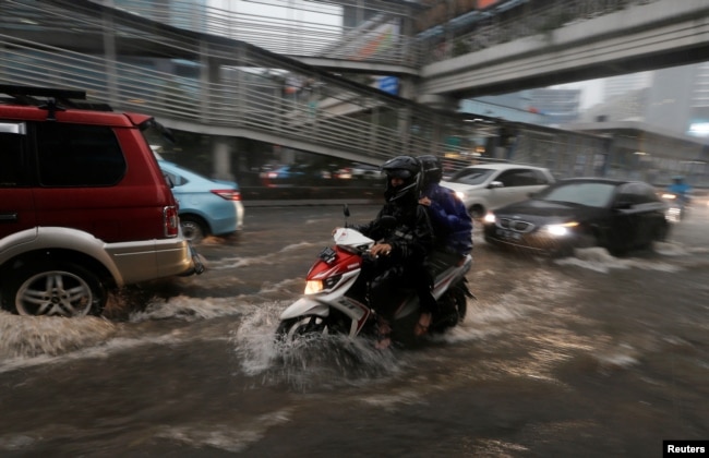 Para pengendara motor menerjang banjir yang menggenang kawasan bisnis Jakarta, 11 Desember 2017. (REUTERS/Beawiharta)