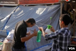 In quiet moments at the two-month old protest camp near Rabaa Adiweya Mosque, children splash each other with water to stay cool, in Cairo, Aug. 6, 2013. (Photo: H. Elrasam for VOA)