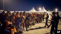 A group of migrants react in front of Spanish Police officers at the port of Algeciras, southern Spain, after being rescued by Spain's Maritime Rescue Service in the Strait of Gibraltar, July 31, 2018. Spain's foreign minister says the European Union's executive branch has allocated 55 million euros ($64.2 million) to manage an upsurge of migrant arrivals mostly from Morocco.