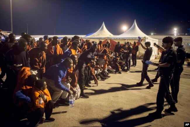 FILE - A group of migrants react in front of Spanish Police officers at the port of Algeciras, southern Spain, after being rescued by Spain's Maritime Rescue Service in the Strait of Gibraltar, July 31, 2018.