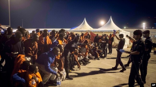 A group of migrants react in front of Spanish Police officers at the port of Algeciras, southern Spain, after being rescued by Spain's Maritime Rescue Service in the Strait of Gibraltar, July 31, 2018. Spain's foreign minister says the European Union's executive branch has allocated 55 million euros ($64.2 million) to manage an upsurge of migrant arrivals mostly from Morocco.