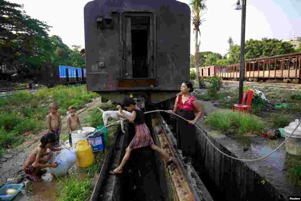 미얀마 양곤의 기차역에서 한 여성과 아이들이 물을 받고 있다.