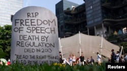 Protesters walk past a mock gravestone that reads 'RIP Freedom of Speech' during a protest against new licensing regulations imposed by the government for online news sites, at Hong Lim Park in Singapore, June 8, 2013.