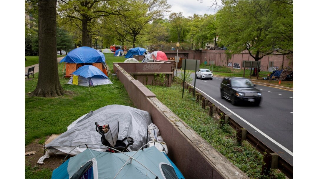 Vehicles exiting from an expressway drive past a homeless encampment near the State Department in downtown Washington, on Friday, April 16, 2021. (AP Photo/Amanda Andrade-Rhoades)