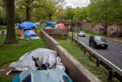 Vehicles exiting from an expressway drive past a homeless encampment near the State Department in downtown Washington, on Friday, April 16, 2021. (AP Photo/Amanda Andrade-Rhoades)