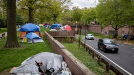 Vehicles exiting from an expressway drive past a homeless encampment near the State Department in downtown Washington, on Friday, April 16, 2021. (AP Photo/Amanda Andrade-Rhoades)
