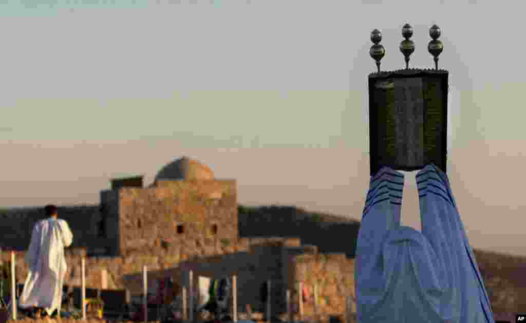 A priest of the ancient Samaritan community holds up a Torah scroll during the pilgrimage for the holy day of the Tabernacles or Sukkot at the religion's holiest site on the top of Mount Gerizim near the West Bank town of Nablus, Oct 29