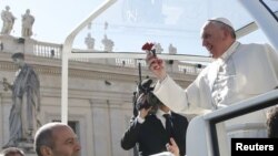 Le pape François tient une fleur jetée par un fidèle, à son arrivée à une audience spéciale avec les fiancés, pour célébrer le jour de la Saint-Valentin, sur la Place Saint-Pierre au Vatican, le 14 février 2014.