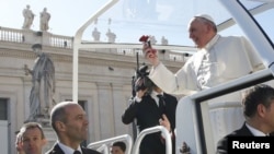 FILE: Pope Francis holds a flower thrown by a faithful as he arrives to lead a special audience with engaged couples, to celebrate Saint Valentine's day, in Saint Peter's Square at the Vatican, Feb. 14, 2014. 