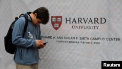 미국 매사추세츠주 케임브리지 시내 하버드대학교 표식 앞을 지나던 사람이 스마트폰을 보고 있다. (자료사진)