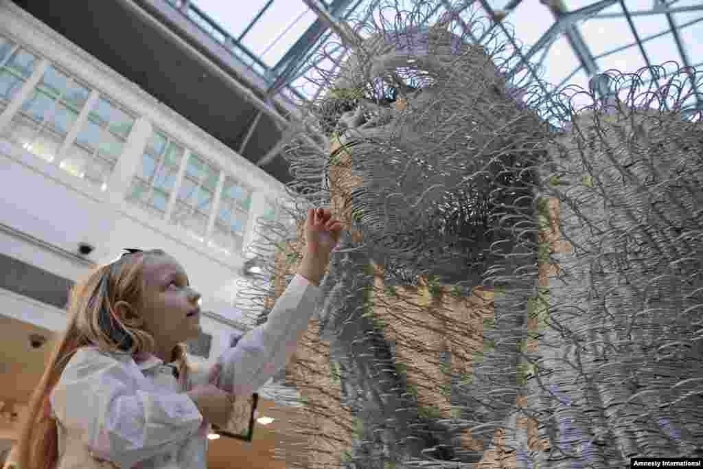 A girl touches an art installation depicting a gorilla entitled 'Silver Back' by artist David Mach during a press preview of a themed auction that features the animal as artistic inspiration, 'Creatures Great and Small', in London.