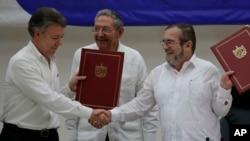 Colombian President Juan Manuel Santos, left, and FARC Commander Timoleon Jimenez shake hands during a signing ceremony of a cease-fire and rebel disarmament deal, in Havana, Cuba, June 23, 2016. Pictured in the center is Cuba's President Raul Castro.
