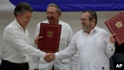 FILE - Colombian President Juan Manuel Santos, left, and Timoleon Jimenez, commander of the Revolutionary Armed Forces of Colombia, or FARC, shake hands during a signing ceremony of a cease-fire and rebel disarmament deal, in Havana, Cuba, June 23, 2016. 