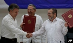 Colombian President Juan Manuel Santos, left, and Timoleon Jimenez, commander of the Revolutionary Armed Forces of Colombia, or FARC, shake hands during a signing ceremony of a cease-fire and rebel disarmament deal, in Havana, Cuba, June 23, 2016.