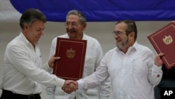 후안 마뉴엘(왼쪽) 콜롬비아 대통령과 티몰레온 히메네즈 콜롬비아 무장혁명군(FARC) 사령관이 23일 쿠바 수도 아바나에서 휴전협정문에 서명한 뒤 악수하고 있다. 