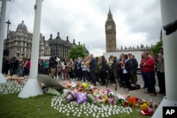 Staff from Britain's opposition Labour Party stand together before placing floral tributes for their colleague Jo Cox, the 41-year-old British Member of Parliament shot to death yesterday in northern England, on Parliament Square outside the House of Parliament in London, Friday, June 17, 2016.