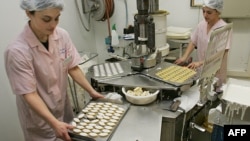 FILE - Two employees prepare 'calissons,' a traditional French candy, in Aix-en-Provence, southern France, Dec. 14, 2005.