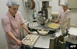 FILE - Two employees prepare 'calisson,' a traditional French candy, in Aix-en-Provence, southern France, Dec. 14, 2005.