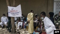 Un homme gare sa moto avant de voter dans un bureau de vote en bordure de route à N'djaména le 11 avril 2021.