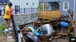 Residentes observan vehículos destruidos dejados por una inundación repentina del río Patapsco, en Ellicott City, Maryland. Mayo 28 de 2018.