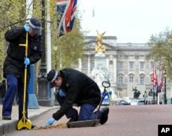 Metropolitan police officers carry out security checks on drains and lamp posts along the Mall ahead of the Royal wedding in London, April 26, 2011