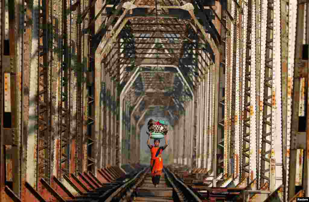 A woman carrying luggage walks along a railway track on the outskirts of Mumbai, India.