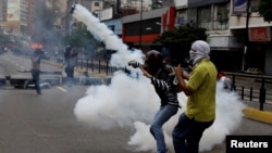 A demonstrator throws a tear gas canister during riots at a rally against Venezuelan president Nicolas Maduro's government in Caracas, Venezuela, June 7, 2017.