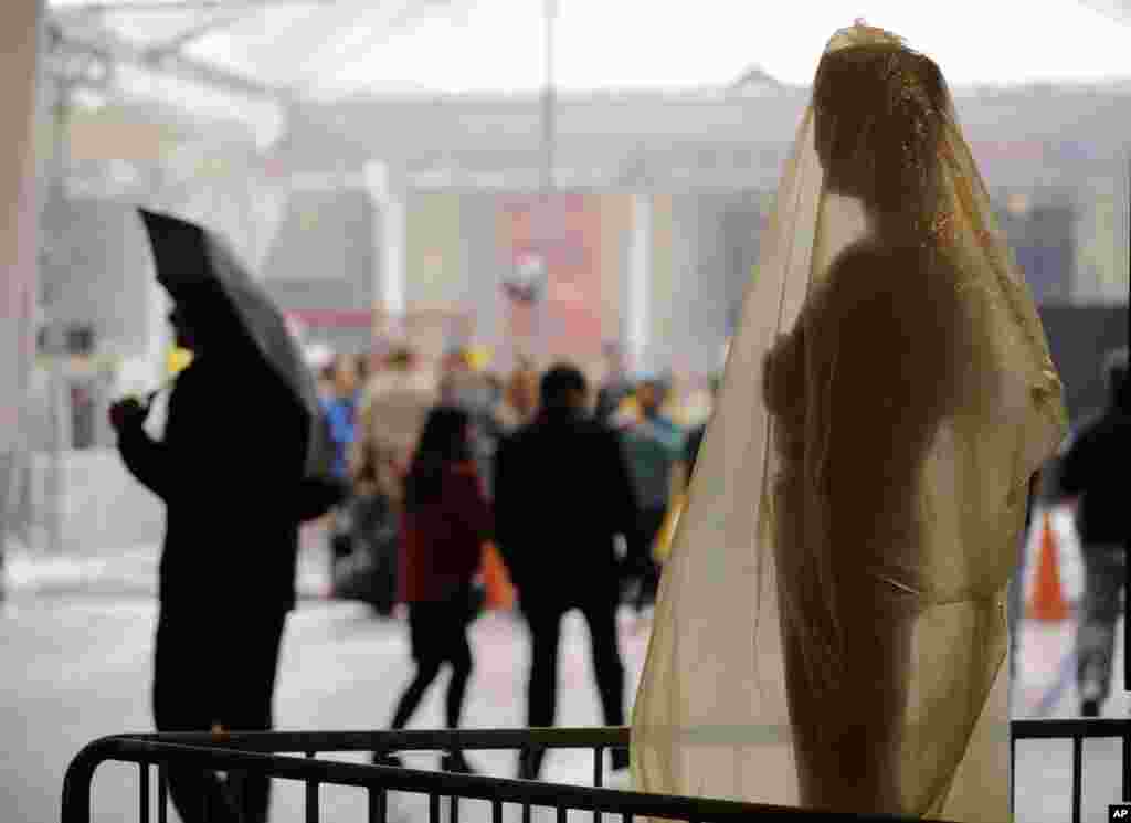 Pedestrians walk by a covered Oscar statue outside the Dolby Theatre, Los Angeles, California, Feb. 28, 2014.