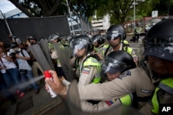 A Bolivarian National Police officer aims pepper spray at opposition leader Henrique Capriles during a protest in Caracas, Venezuela, June 7, 2016.