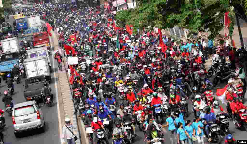 Workers ride their motorcycles along a street during a demonstration in an industrial area of Tangerang, on the outskirts of Jakarta, Oct. 3, 2012. 