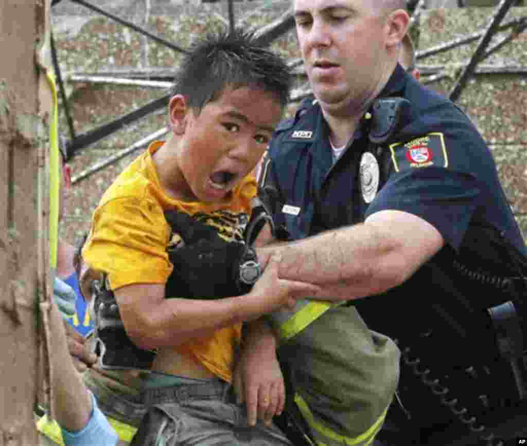 A boy is pulled from beneath a collapsed wall at the Plaza Towers Elementary School following a tornado in Moore, Okla., Monday, May 20, 2013. 