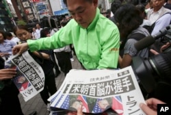 A staff of a Japanese news paper Yomiuri distributes an extra edition of the newspaper reporting about the summit between U.S. President Donald Trump and North Korean leader Kim Jong Un in Singapore, at Shimbashi Station in Tokyo, June 12, 2018.
