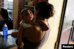 FILE - Ericka Torres holds her 3-month-old son, Jesus, who was born with microcephaly, at their home in Guarenas, Venezuela, Oct. 5, 2016.