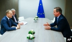 European Council President Donald Tusk, left, and European Commission President Jean-Claude Juncker, second left, participate in a meeting with British Prime Minister David Cameron during an EU summit in Brussels, Feb. 19, 2016.