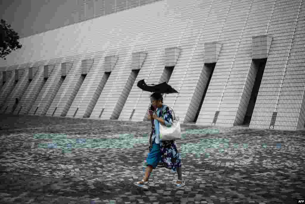 A woman walks on a promenade that runs along Victoria Harbor in Hong Kong.