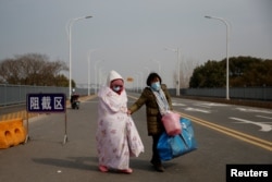 A cancer patient and her mother coming from Hubei province cross a checkpoint at the Jiujiang Yangtze River Bridge in Jiujiang, Jiangxi province, China, as the country is hit by an outbreak of a new coronavirus, February 1, 2020.