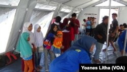 Para Relawan dari Komunitas Pecinta Alam Malang Satu Jiwa, Jawa Timur saat membawakan sesi pelajaran gempa bumi melalui permainan dan nyanyian di tenda kelas darurat Sekolah Dasar Negeri Lolu, Kabupaten Sigi, Sulawesi Tengah, Kamis, 25 Oktober 2018. (Foto: VOA/Yoanes Litha).