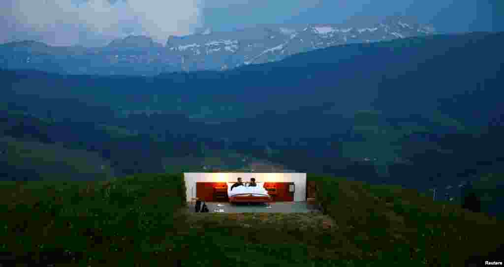 Raphael and Mirjam (R) pose as the first "guests" in the bedroom of the Null-Stern-Hotel (Zero-star-hotel) land art installation by Swiss artists Frank and Patrik Riklin, on Mount Saentis near Gonten, Switzerland.