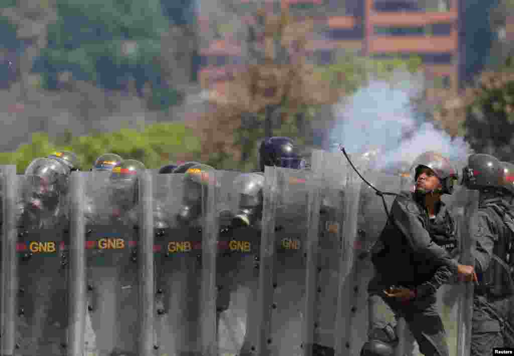 A member of the National Guard throws an object toward opposition supporters during a rally against the government of Venezuela's President Nicolas Maduro and to commemorate May Day in Caracas, May 1, 2019.