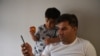 FILE - Special Immigrant Visa Afghan Abdul Aman Sediqi, a U.S. Special Immigrant Visa (SIV) recipient, and his son Elyan watch news from Kabul following their evacuation from Afghanistan in Houston, Texas, Aug 26, 2021. 