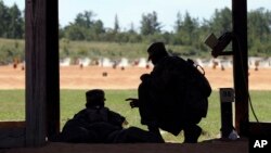 FILE - A U.S. Army recruit is instructed by a drill sergeant, right, during live-fire marksmanship training at Fort Jackson, S.C., Aug. 17, 2016.