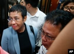 Maria Ressa, the award-winning head of a Philippine online news site Rappler that has aggressively covered President Rodrigo Duterte's policies, is escorted into another room following her arrest by National Bureau of Investigation agents in a libel case,