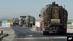 FILE - A convoy of oil trucks passes a Kurdish police (Assayesh) checkpoint, as they transport fuel produced in Kurdish-held areas in the east to other areas controlled by the same U.S.-backed group to the west, on a highway in Hassakeh province, Syria, April 4, 2018.
