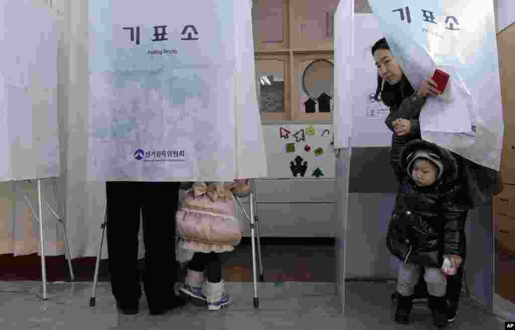 Seorang warga Korea Selatan di tempat pemilihan suara bersama anak laki-lakinya (19/12). (AP/Lee Jin-man)