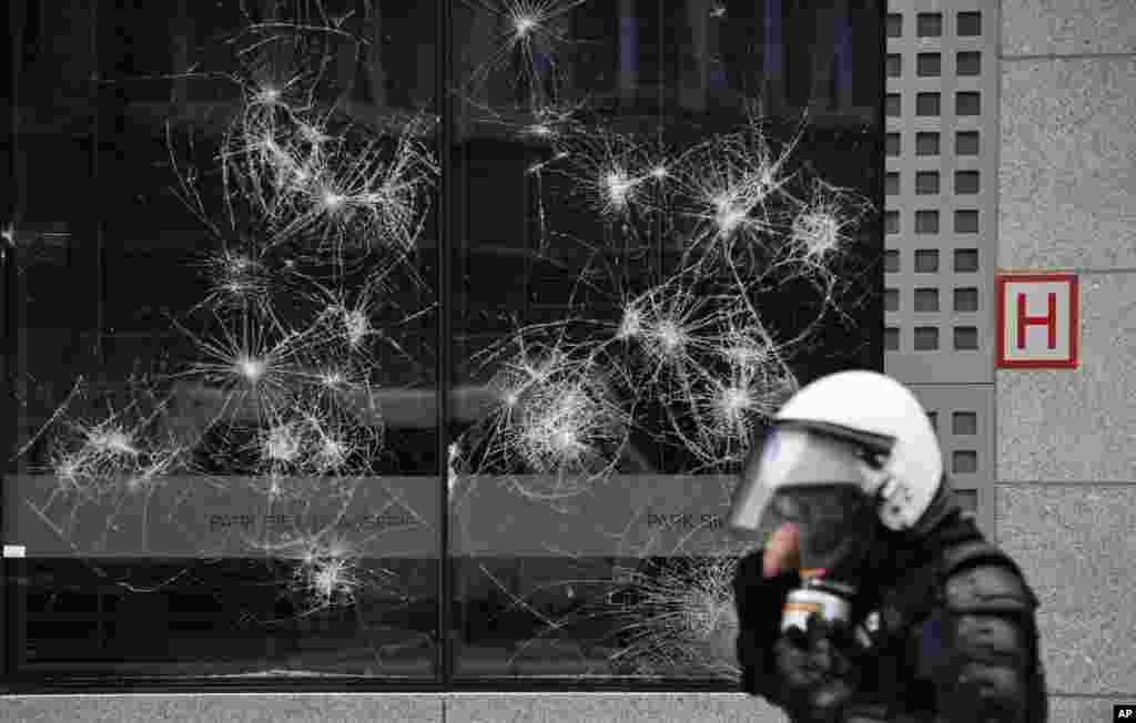 A police officer walks by a damaged building in the European Union quarter during a demonstration against COVID-19 measures in Brussels, Belgium.