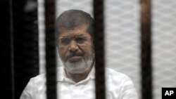 FILE - Egypt's ousted Islamist President Mohamed Morsi sits in the defendant cage in the Police Academy courthouse during a court hearing on charges of inciting the murder of his opponents, in Cairo, Egypt, Nov. 3, 2014. 